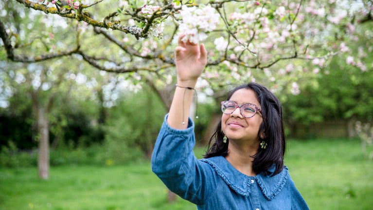 A visitor admiring blossom in the orchard at Quarry Bank, Cheshire
